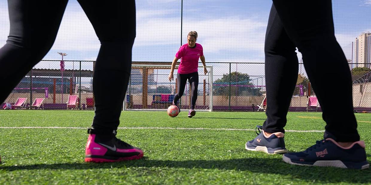 Thais Demétrio em um campo de futebol prestes a chutar a bola