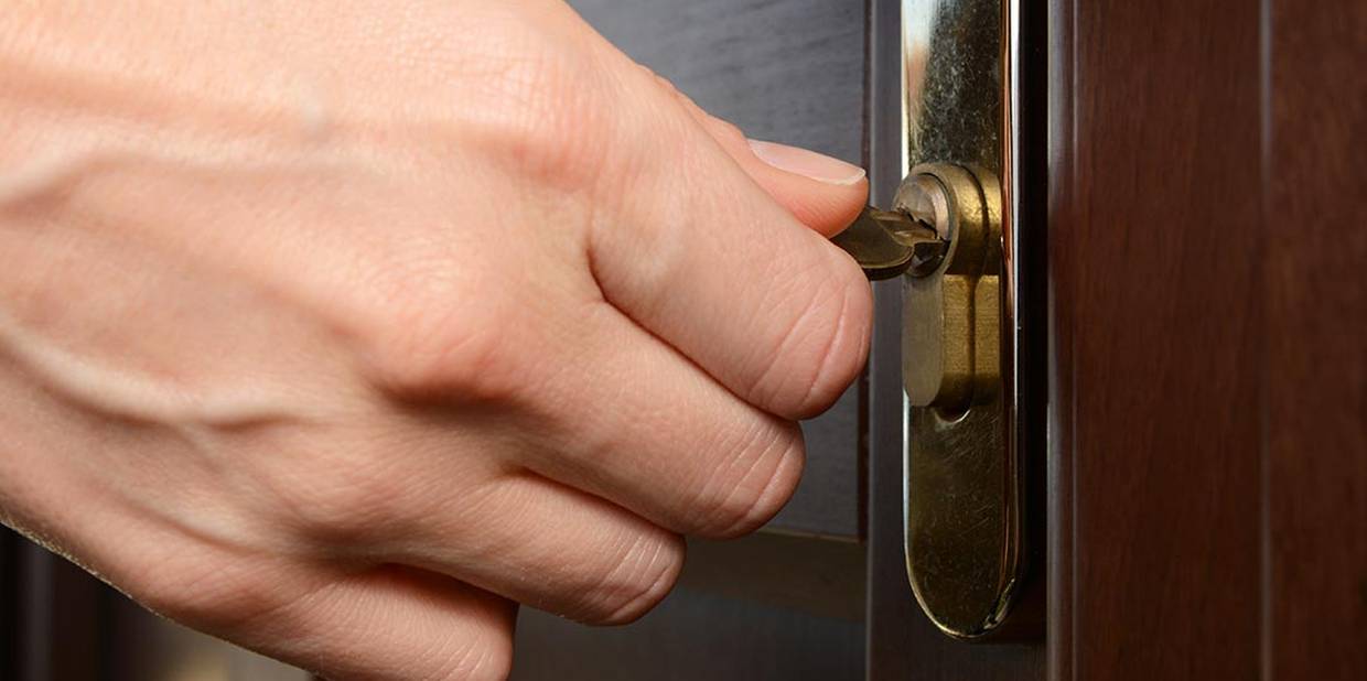 Mão gira chave em fechadura de porta