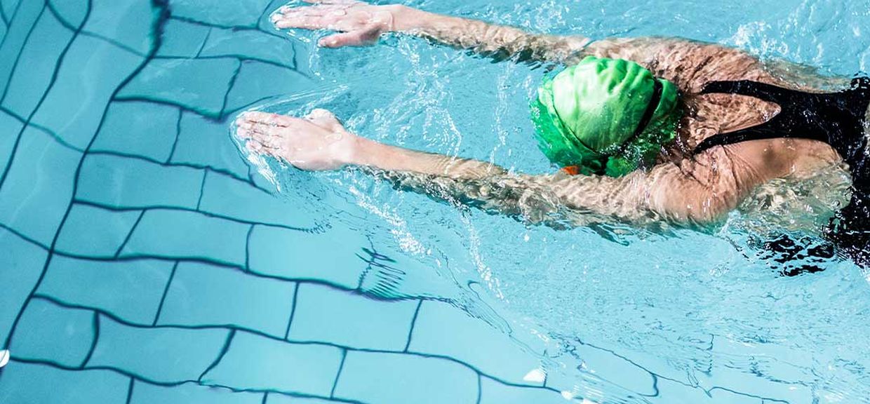 Pessoa nadando em uma piscina com touca verde