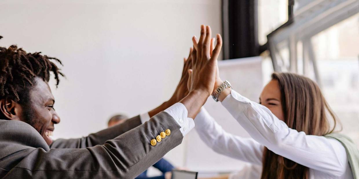 Um homem e uma mulher em um ambiente de escritório comemoram uma conquista