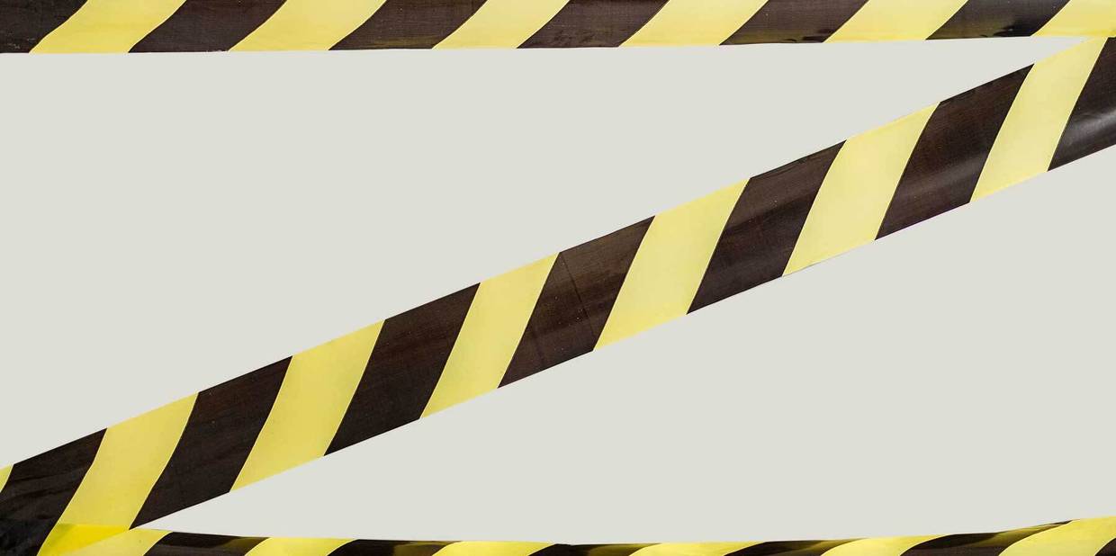 Faixas de segurança listradas de amarelo e preto aparecem em um fundo cinza