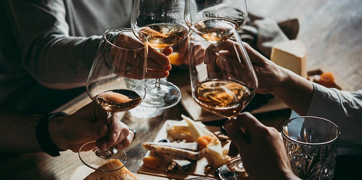 Pessoas fazem brinde com taças de vinho.