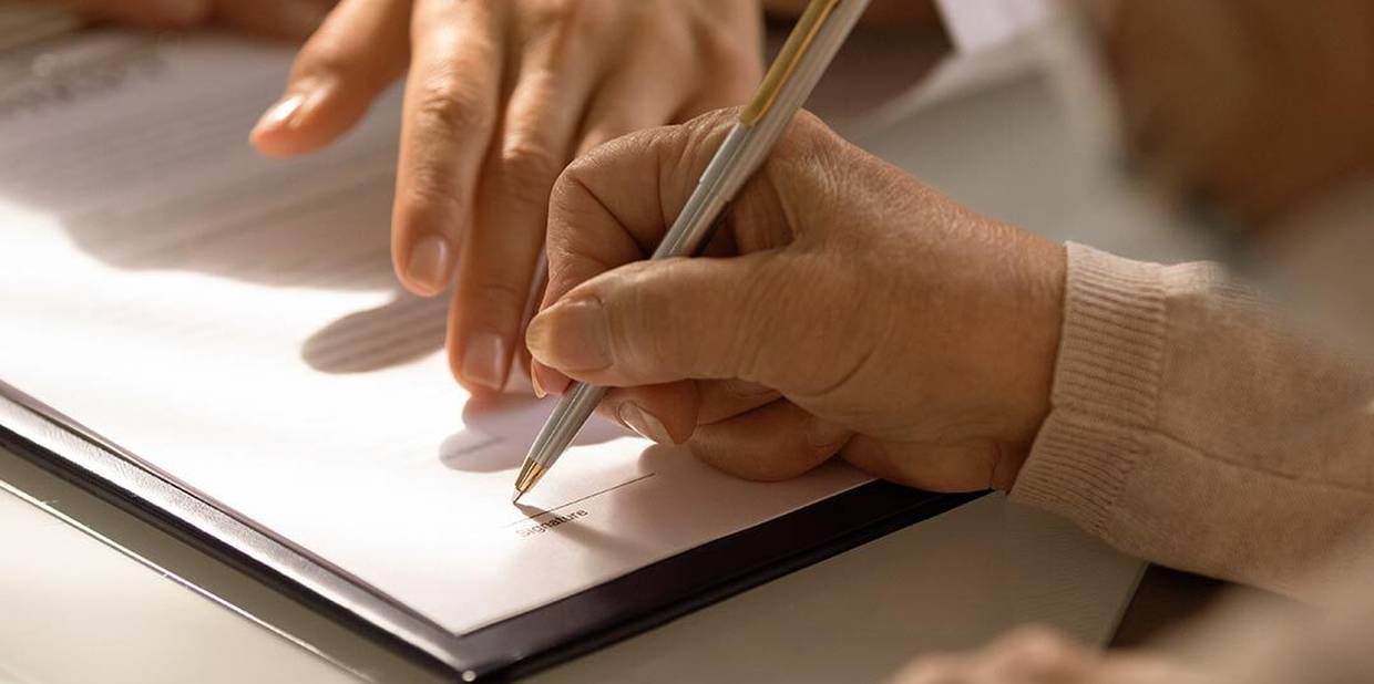 Mão segura caneta e escreve em papel