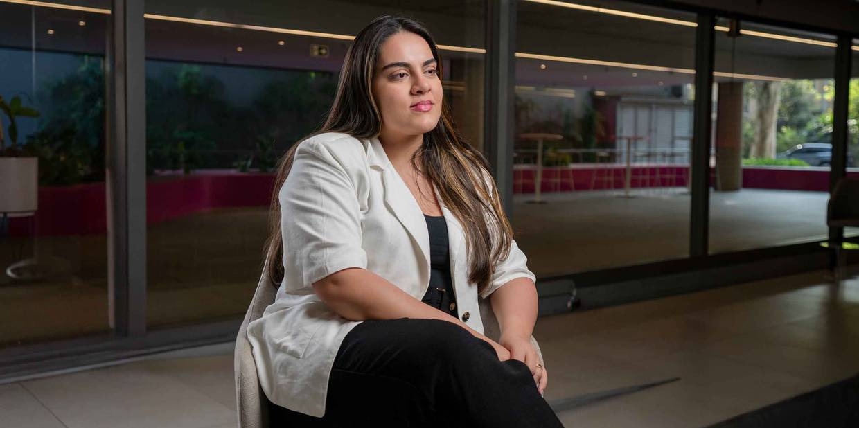 Uma mulher está sentada em uma cadeira, com as mãos na perna