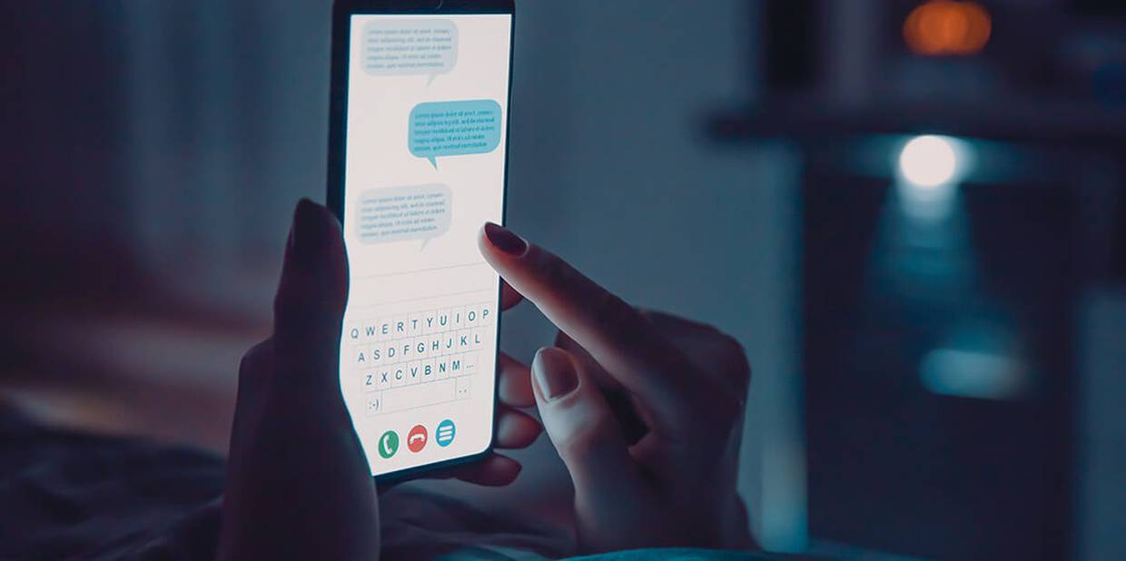 Pessoa mexe em celular à noite