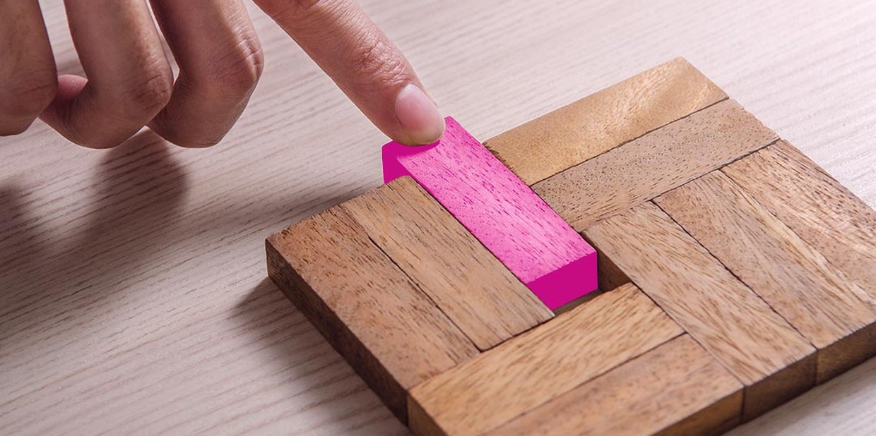 Close de mão puxando uma pecinha de madeira na cor magenta
