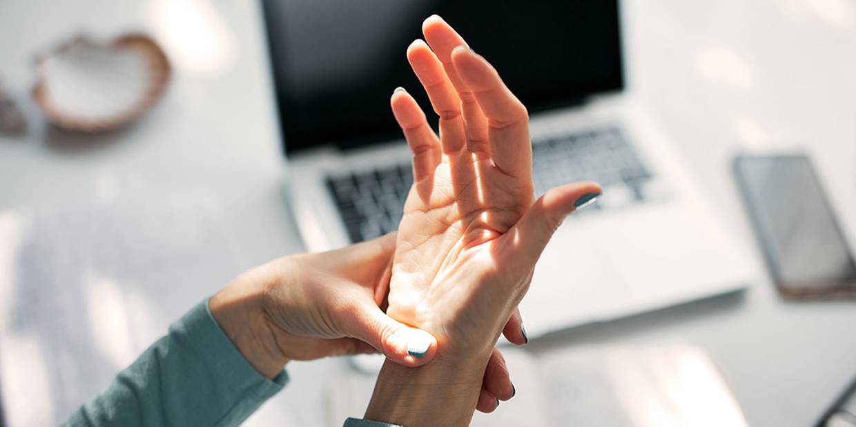 Pessoa toca em sua própria mão e no punho