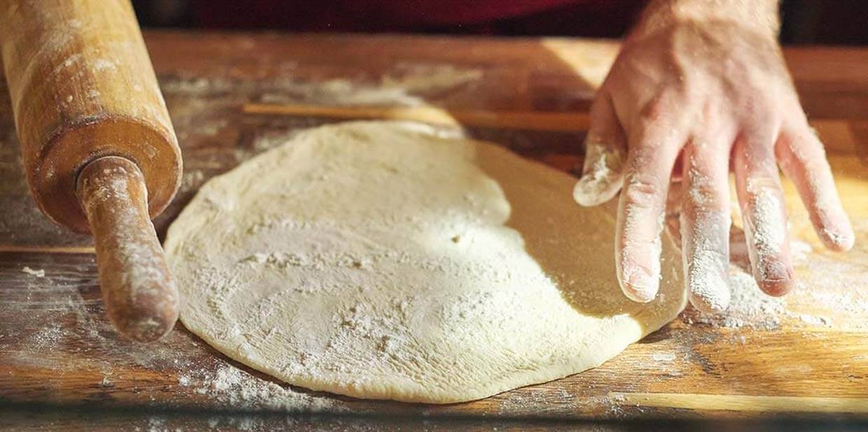 Pessoa prepara massa com farinha