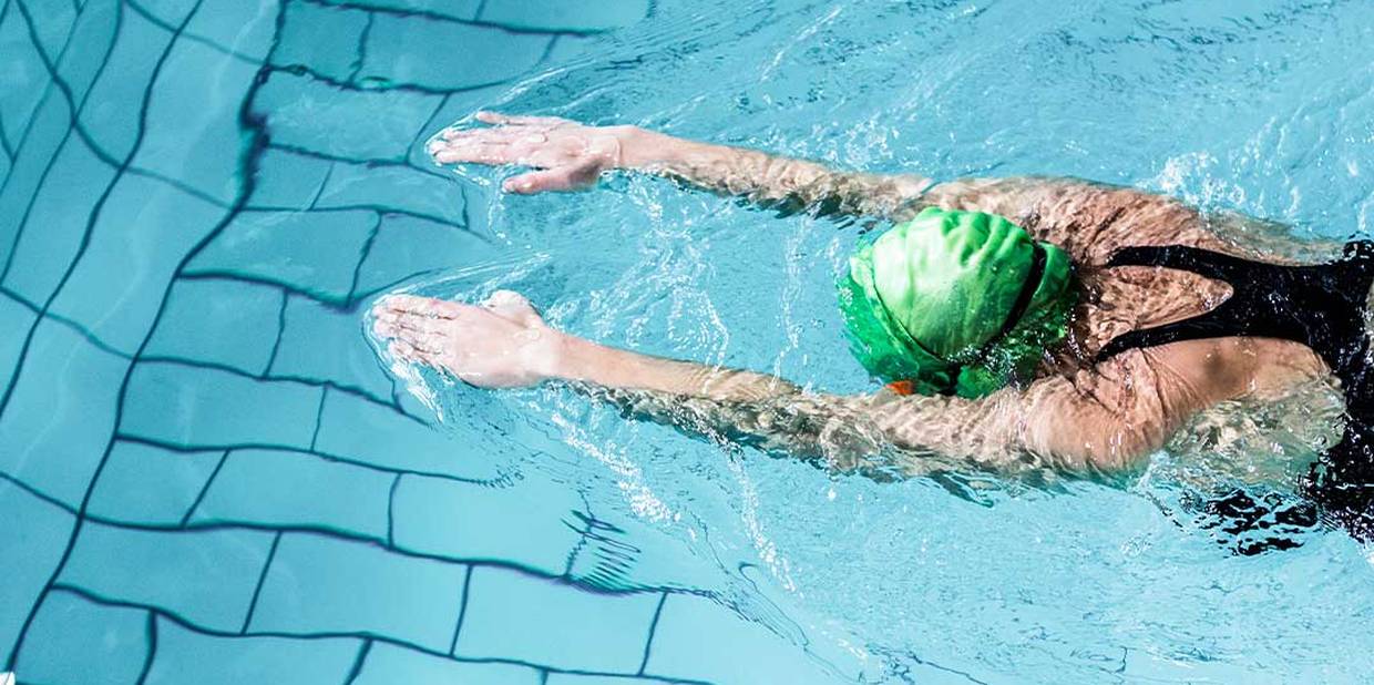 Pessoa nadando em uma piscina com touca verde