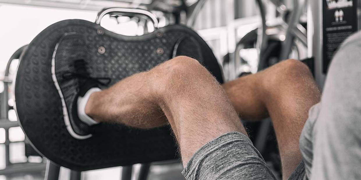 Homem faz leg press em academia