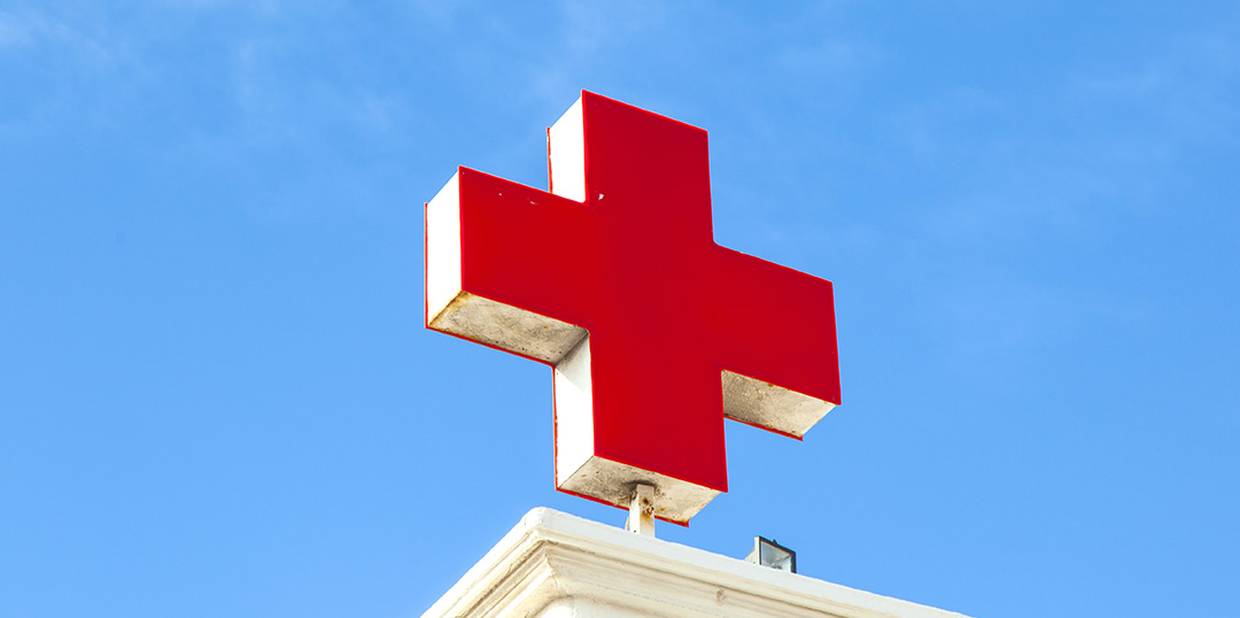 Close de uma cruz vermelha sobre um prédio, em alusão a um hospital