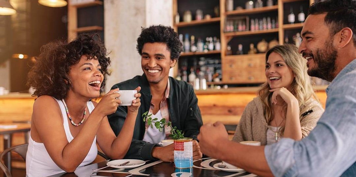 Colegas de trabalho conversam e riem em café