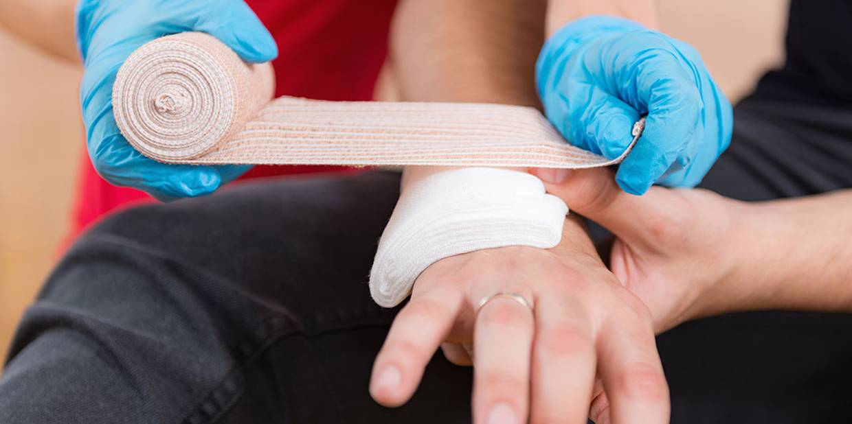 Pessoa recebendo primeiros socorros em uma ferida