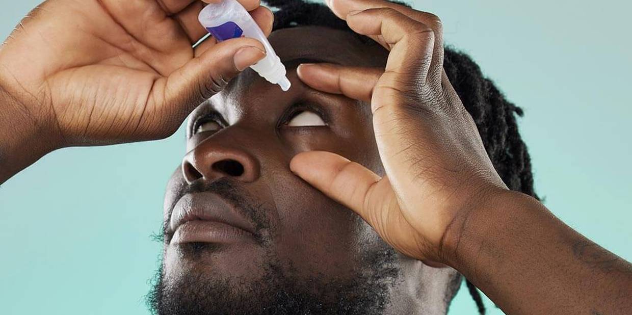 Pessoa aplica colírio nos olhos