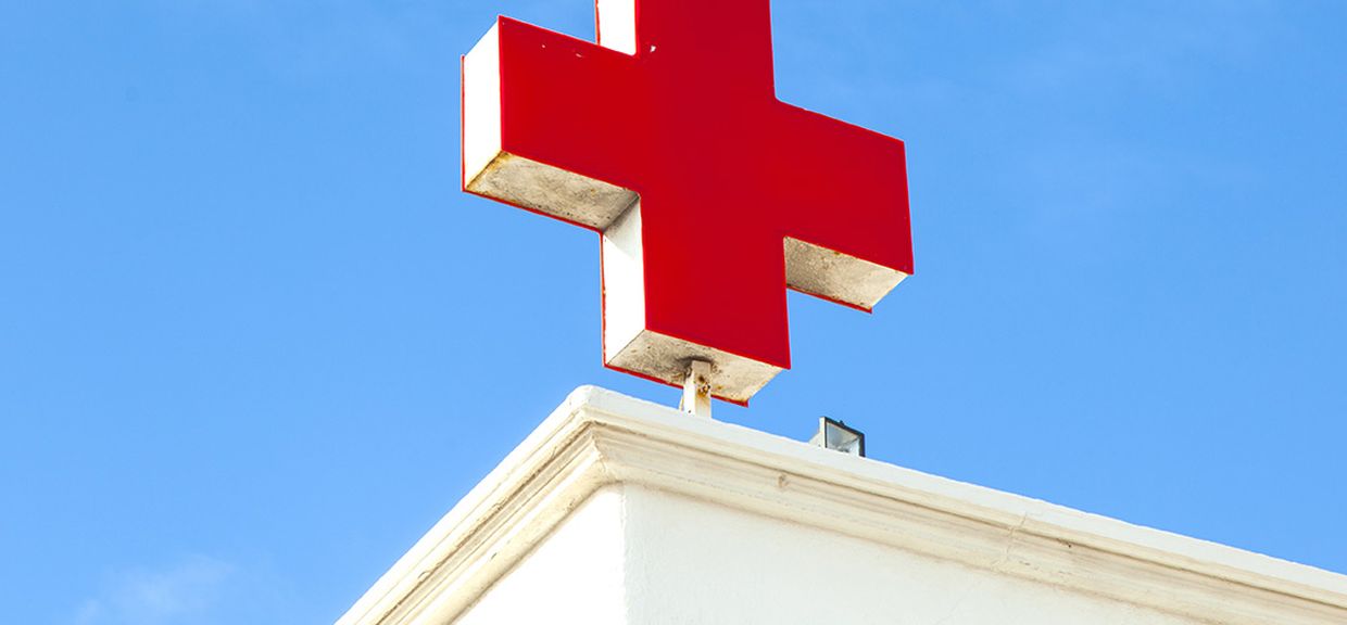 Close de uma cruz vermelha sobre um prédio, em alusão a um hospital