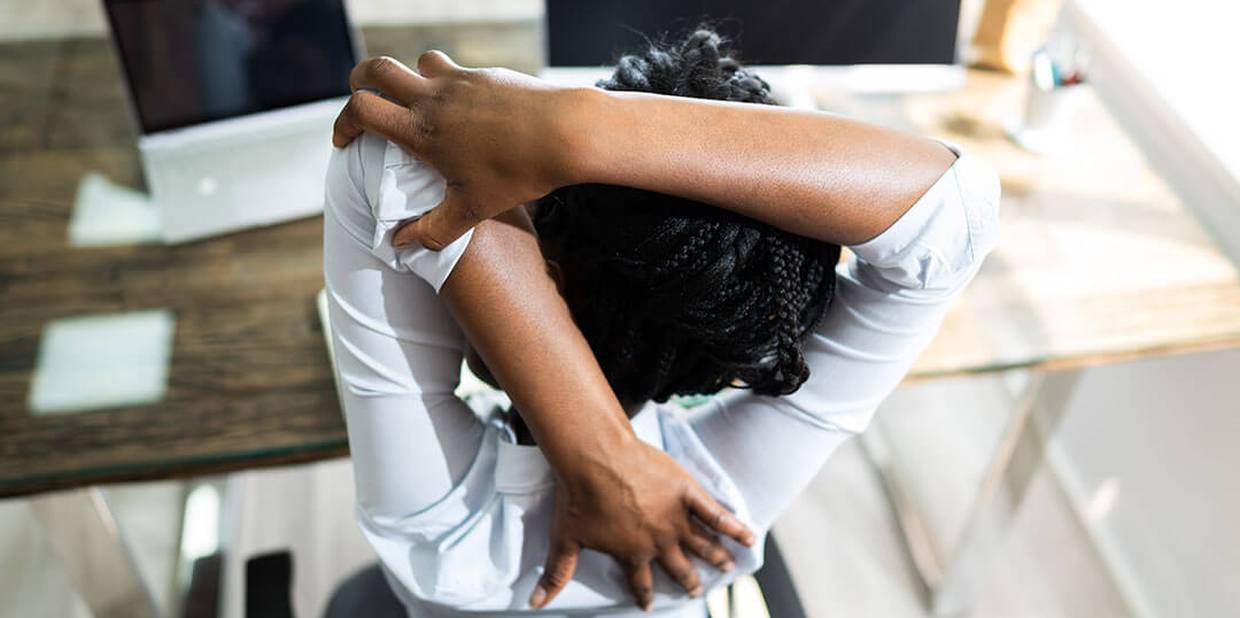 Pessoa faz alongamento em frente à tela do computador