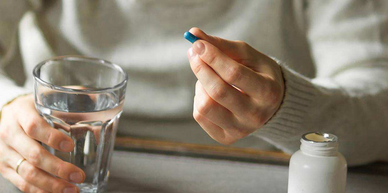 Pessoa segura comprimido e copo de água