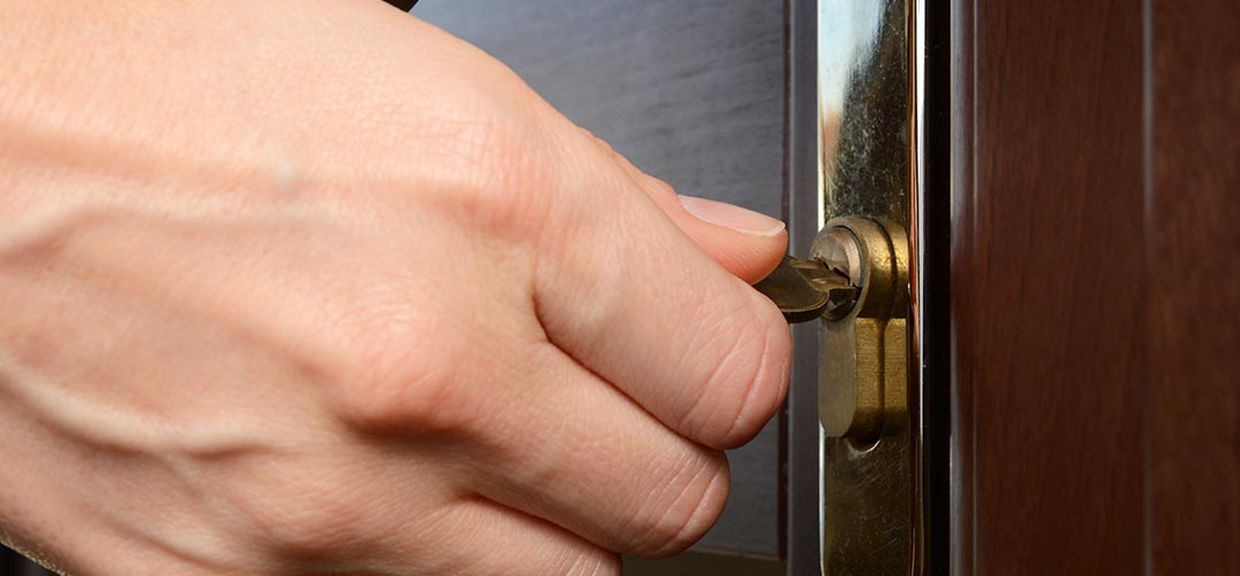 Mão gira chave em fechadura de porta