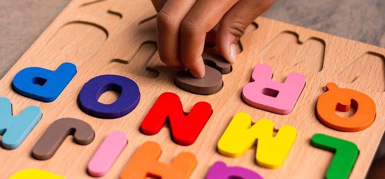 Criança brinca com letras do alfabeto de madeira