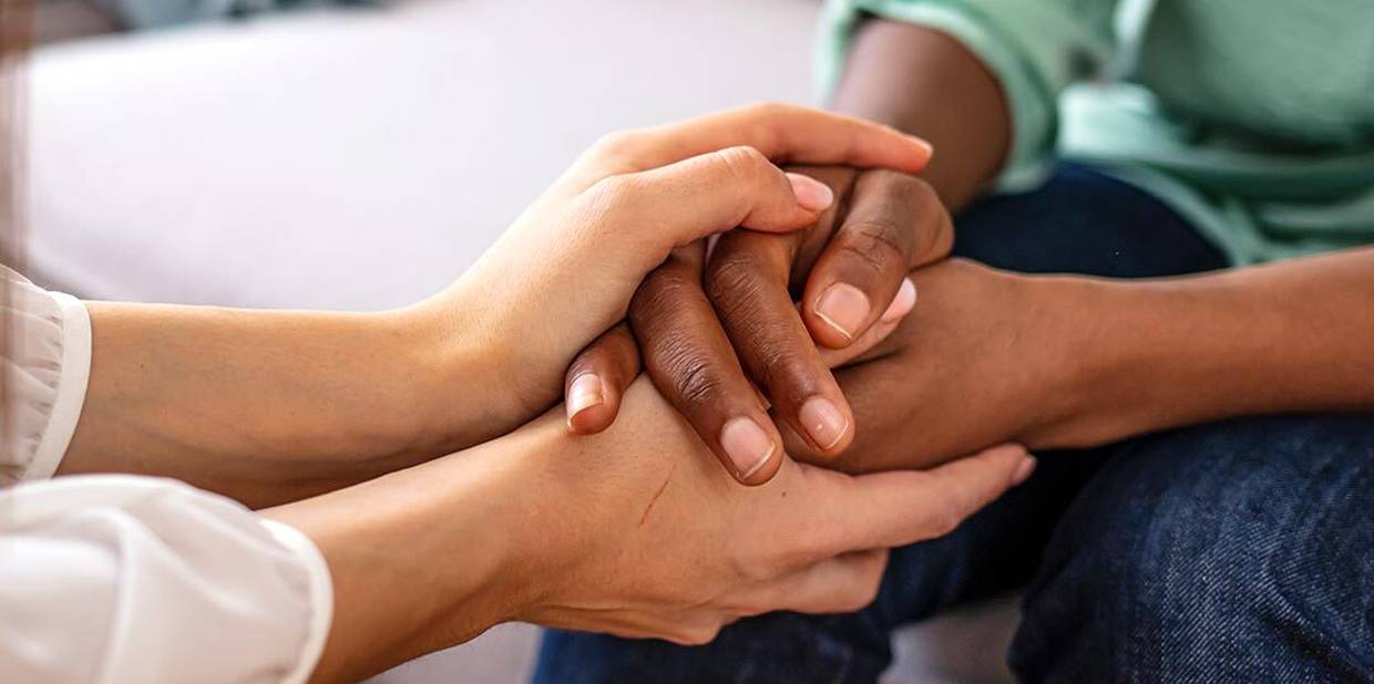 Uma pessoa segura as mãos da outra, como se estivesse apoiando-a
