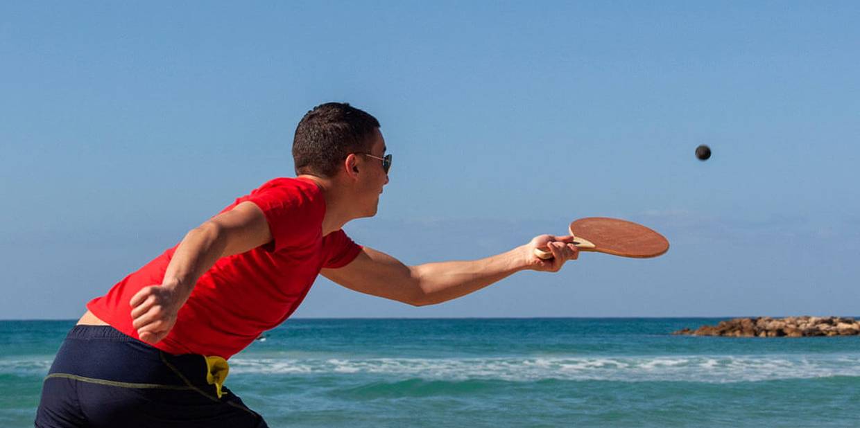 Pessoa joga frescobol na praia