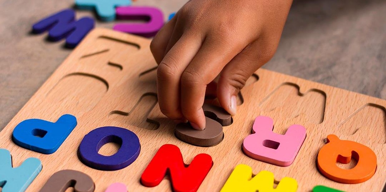 Criança brinca com letras do alfabeto de madeira
