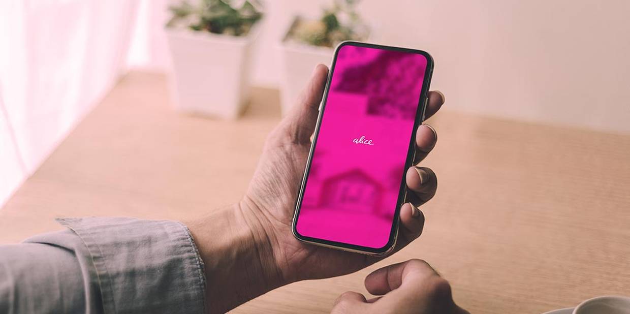 Mãos segurando um celular que mostra o app da Alice