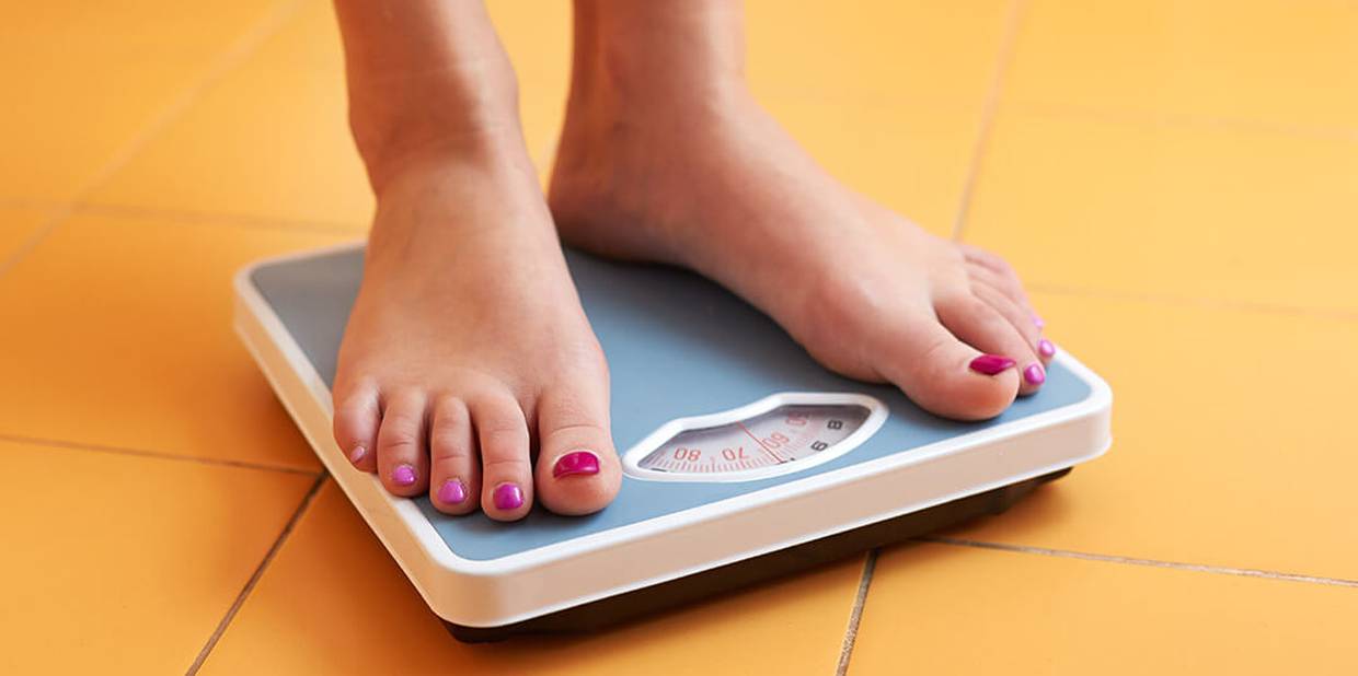 Pessoa com as unhas dos pés pintadas sobe em balança